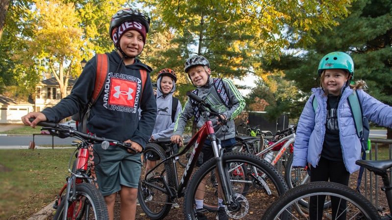 Smiling kids leaving school on their bikes wearing helmets