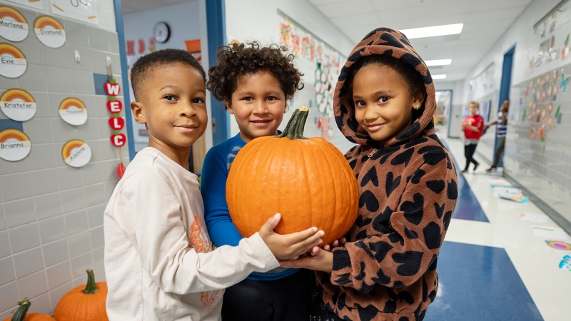 Kindergarteners hold a pumpkin