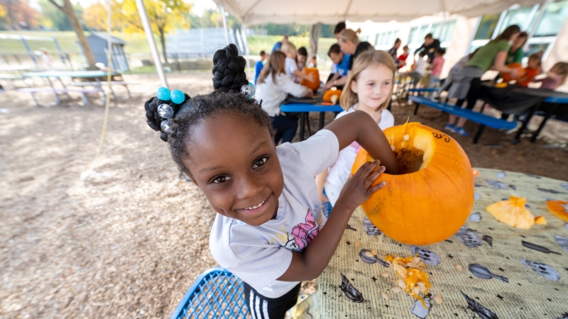 A student cleans out a pumpkin. 