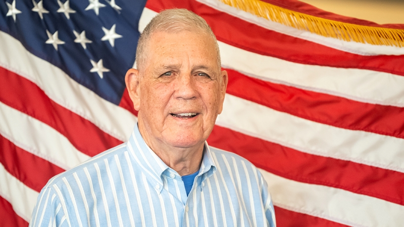 Rowlett "Moose" Bruce stands in front of a flag