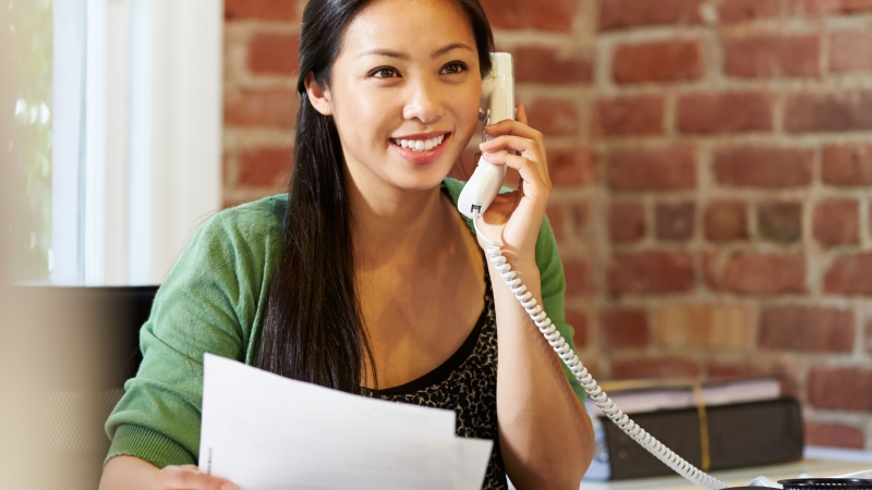 woman holding papers while on the phone