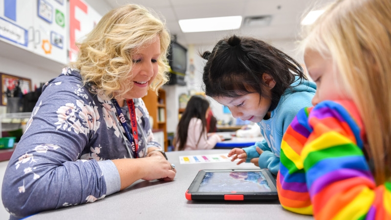 Teacher working with a student who is using an iPad