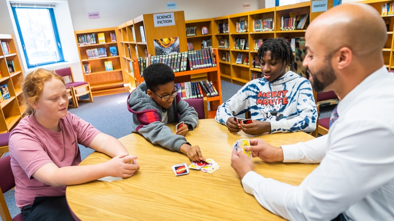 An administrator plays uno with students