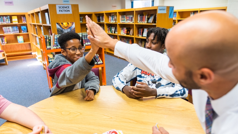 An assistant principal high fives a student