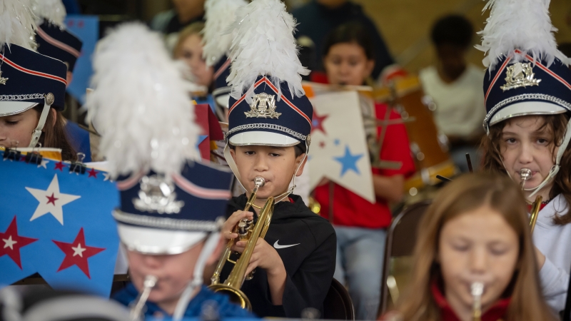 Boy in band hat with plume plays trumpet