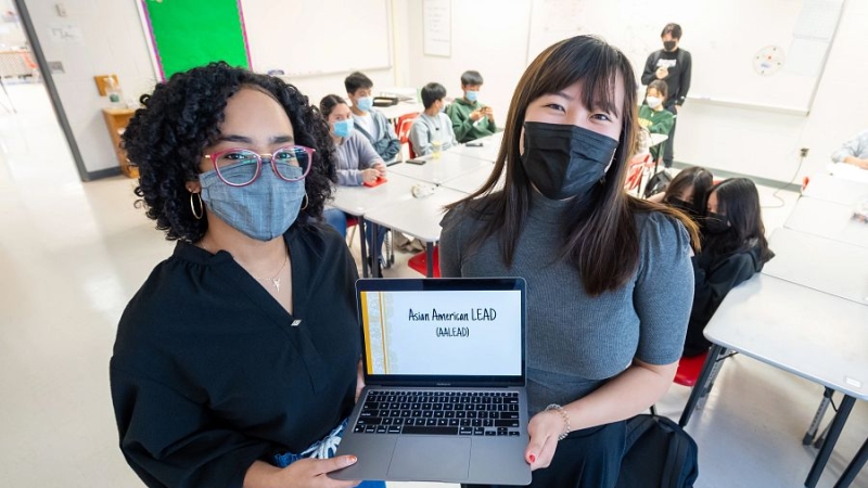 two volunteers standing together holding a laptop