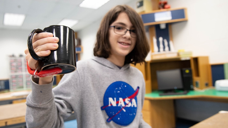 A Rachel Carson MS student shows a "third thumb" device that aids people with arthritis in maintaining a grip on coffee cups.