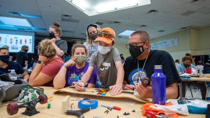 Incoming Glasgow Middle School student Oliver DiGeronimo consults with educators on his skateboard's design.