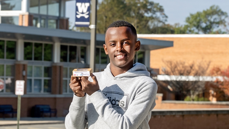 Heman Bekele, winner of 3M's America's Top Young Scientist challenge, stands in front of W.T. Woodson High School.