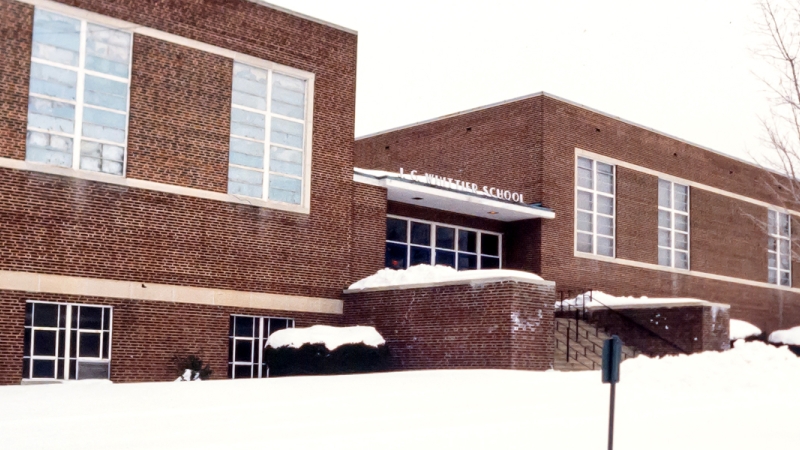 Photograph of the main entrance of Whittier Intermediate School at the school’s City of Falls Church location. The ground out front is covered in snow.