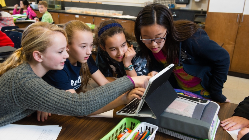 photo of students working together on a tablet