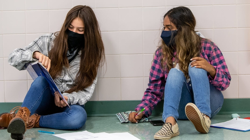 Two high school students studying in hallway