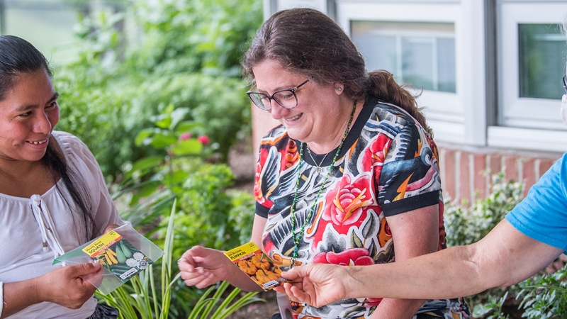 Lynbrook Elementary parent Lidia Gonzalez discusses seed packets with master gardener Mary Kent and environmental educator Rayanne Pirozzi.