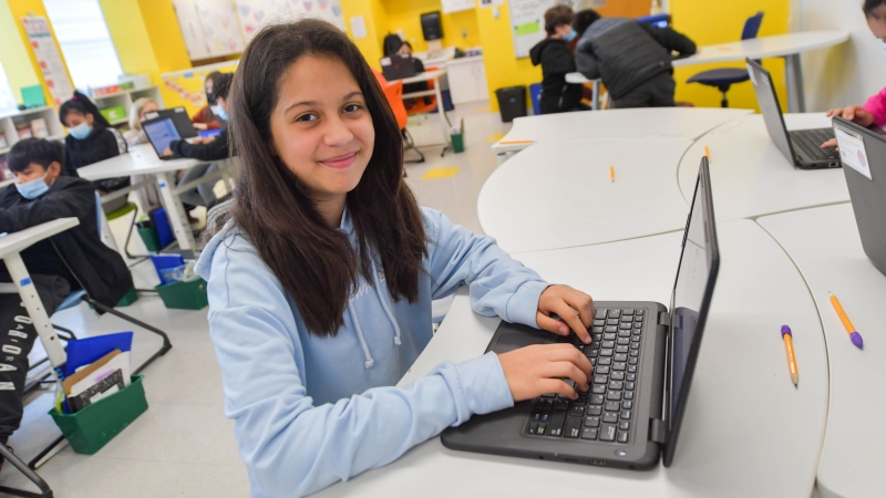 female student typing on laptop in classroom