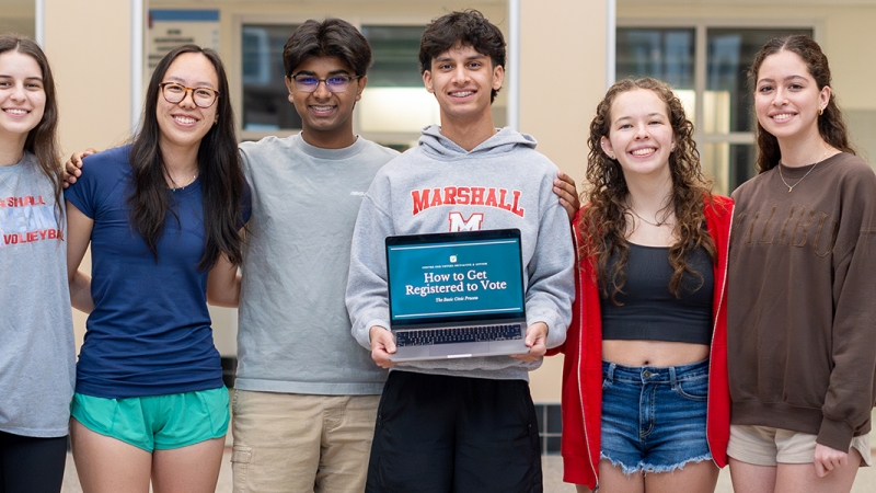 Marshall High School students behind legislation in Congress to boost youth voter turnout pose with laptop showing voter registration guidance.