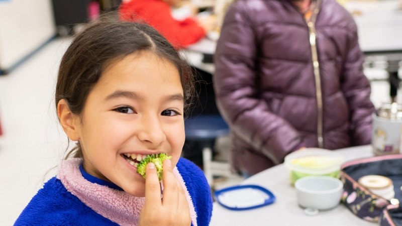 student eating broccoli