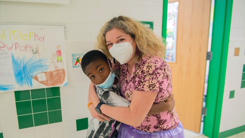 School staff member hugs a student