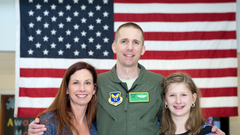 Military family in front of U.S. flag.