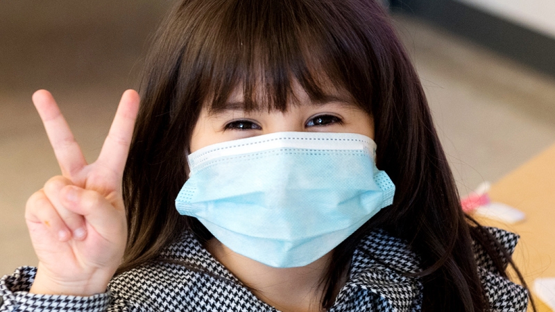 girl with mask giving peace sign