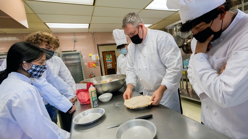 Falls Church High culinary students observe their instructor preparing a crust.