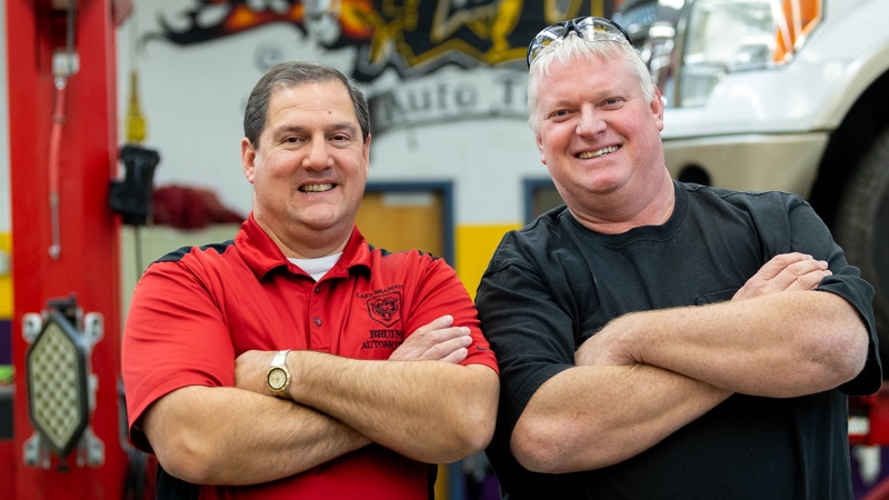 Dominic Prakash and David Plum stand in front of a Ford Mustang in the Lake Braddock Secondary School auto workshop.