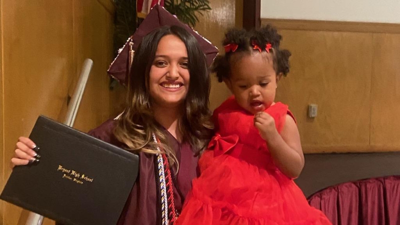 Bryant High School senior Anyeli Salguero walks the graduation stage with her 20-month old daughter and high school diploma in hand.