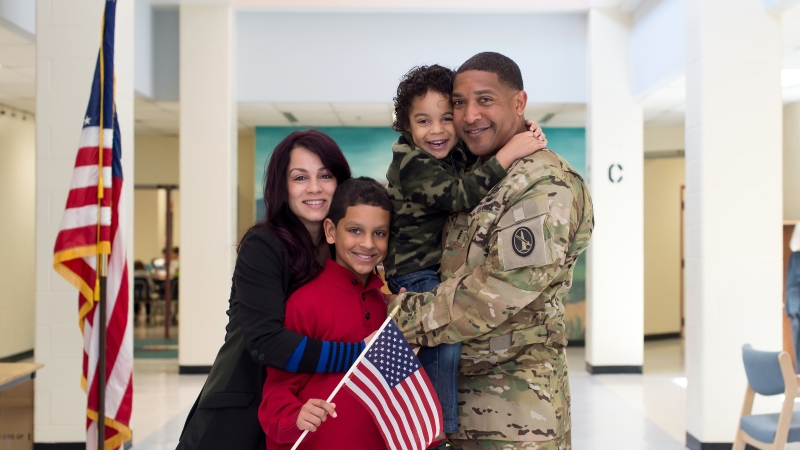 a family standing together smiling with dad in a military uniform