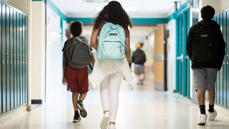 students walking in hallway with backpacks