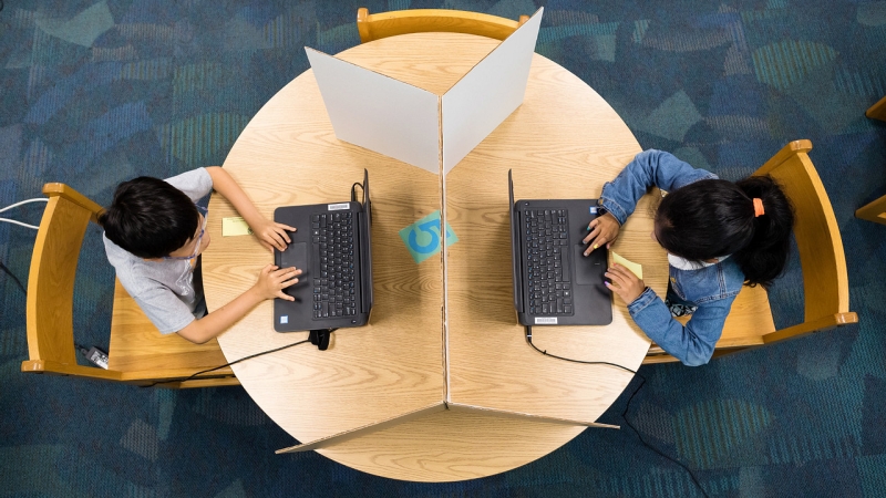 aerial view of 2 students on laptops at study carrels at a round table