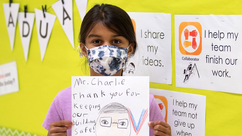 girl hold up thank you letter to school custodian