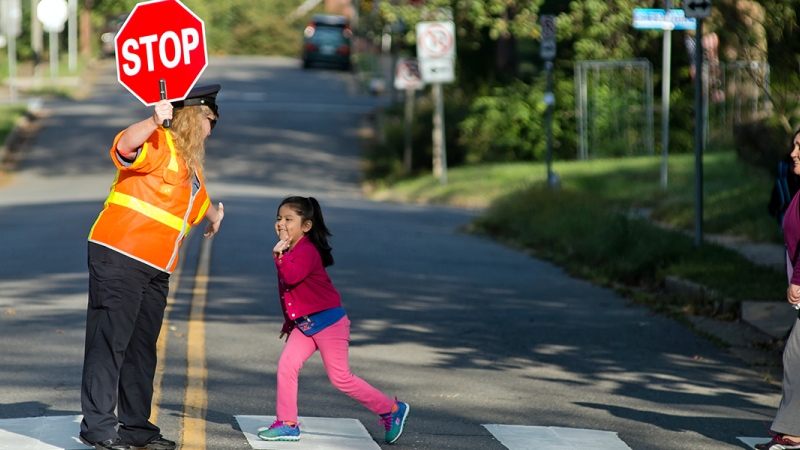girl and mother crossing street with crossing guard