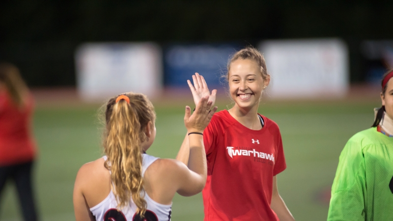 Photo of two female athletes giving each other a high five