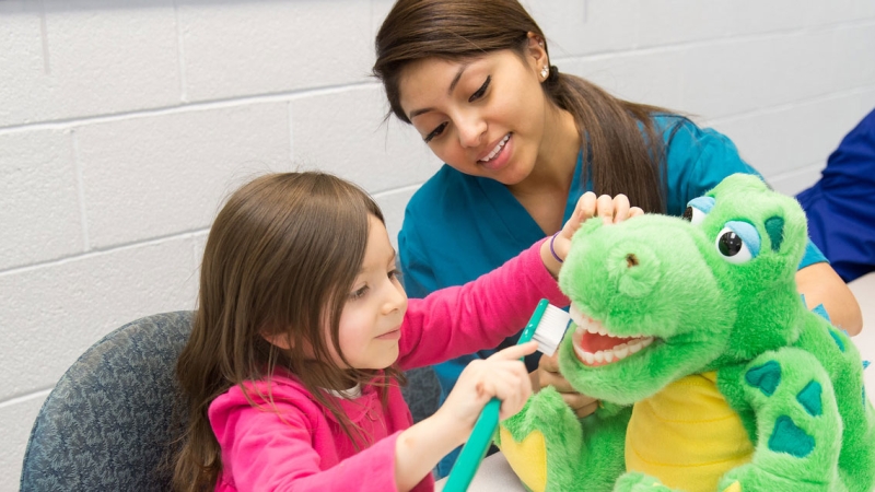 girl brushing stuffed animal teeth