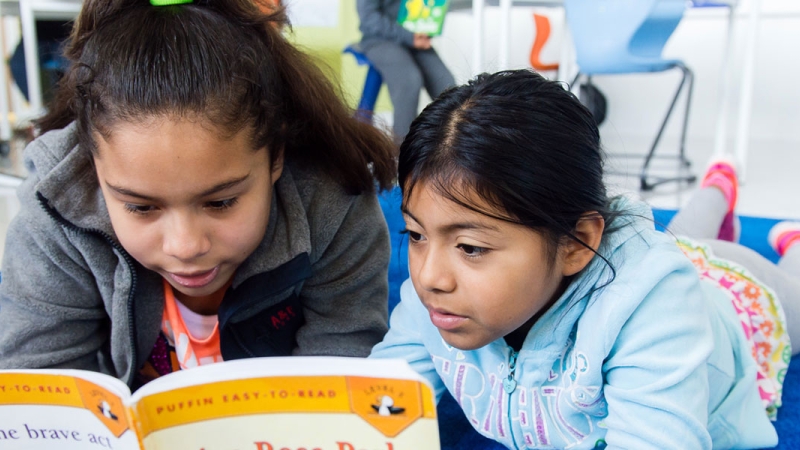 Photo of two students reading a book