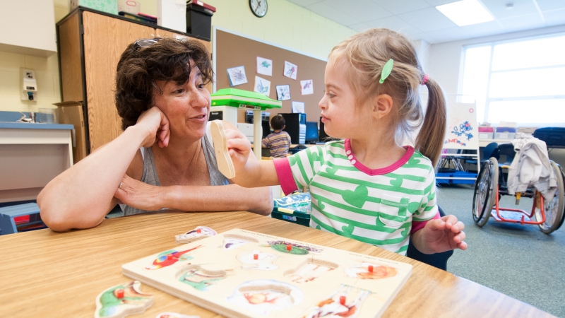 Photo of student putting together a puzzle with a teacher