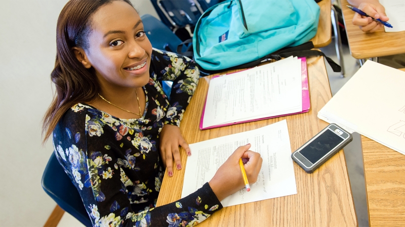 Photo of a female student writing at her desk