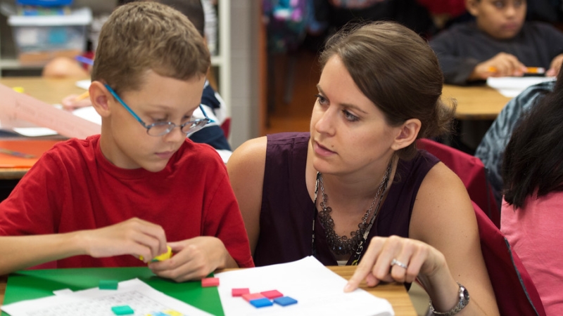 photo of an adult working with a student in a classroom