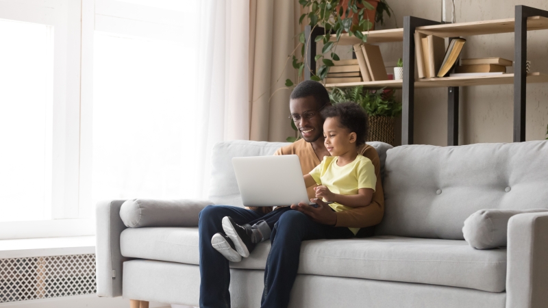 boy and his son sitting on a couch with a laptop