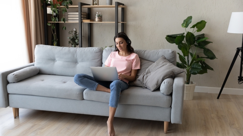 woman sitting on the couch with a laptop and headphones