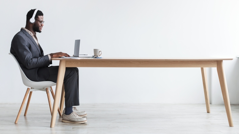 person sitting at a table using a laptop and headset for virtual meeting