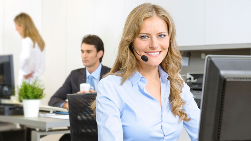 blonde woman with a phone headset using computer