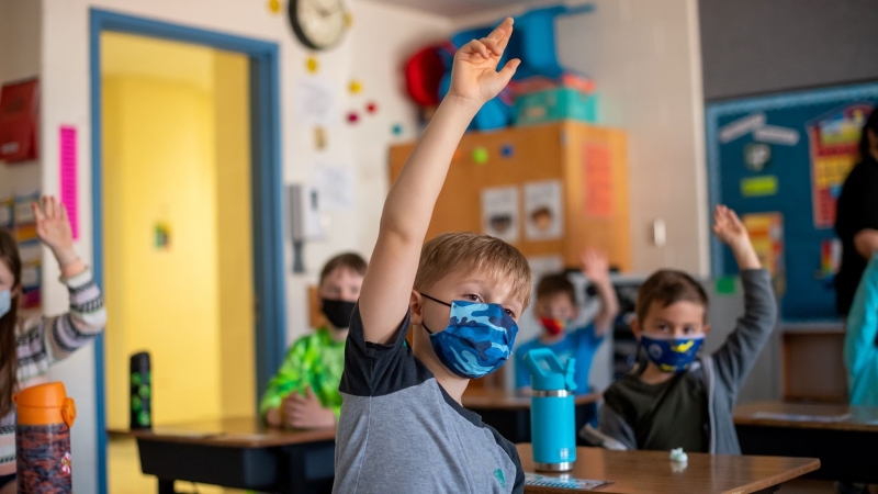 Student in mask with hands raised. 