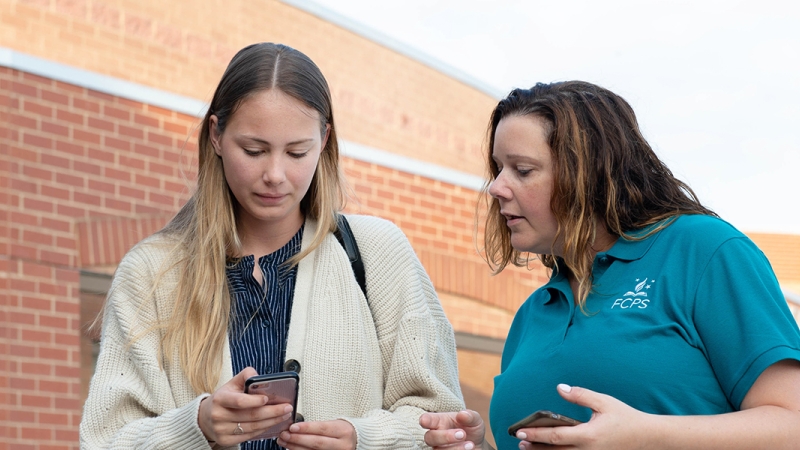 staff member and student viewing a mobile phone