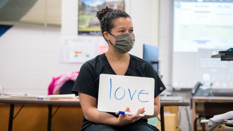 Teacher displaying the word 'love' on a sign in her classroom.