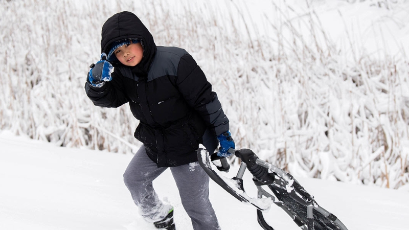 child pulling sled up the hill