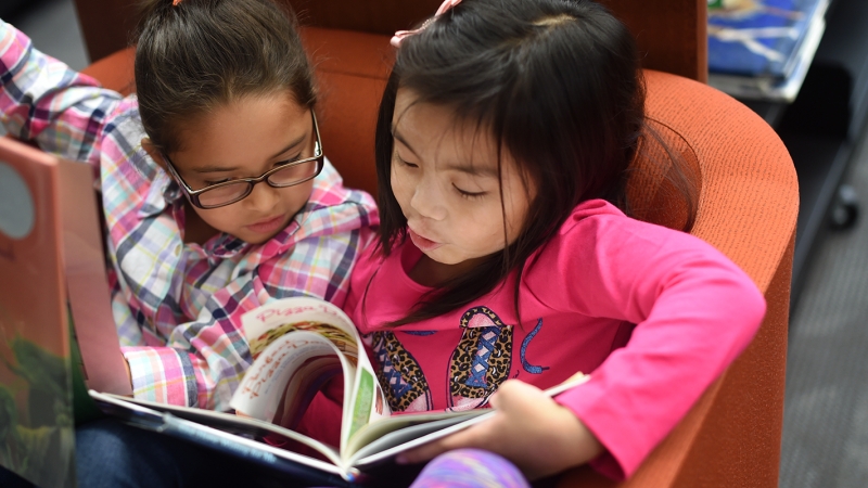 Photo of two students sharing a book