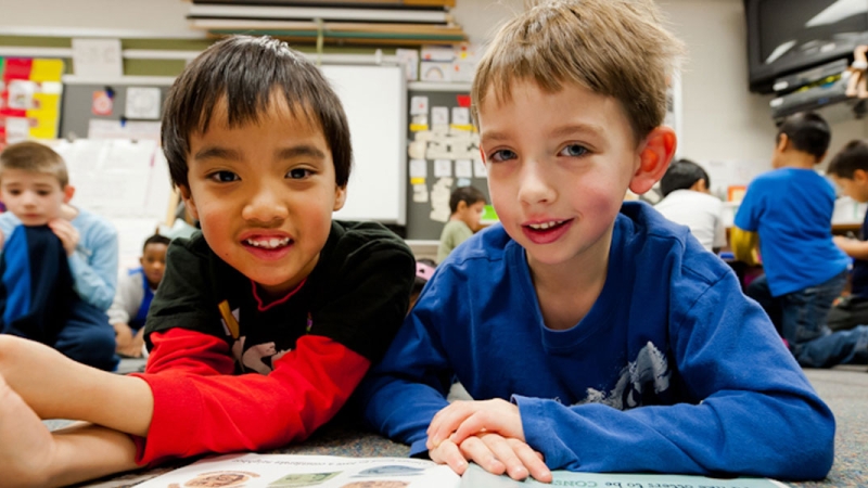 Photo of two elementary male students with a book