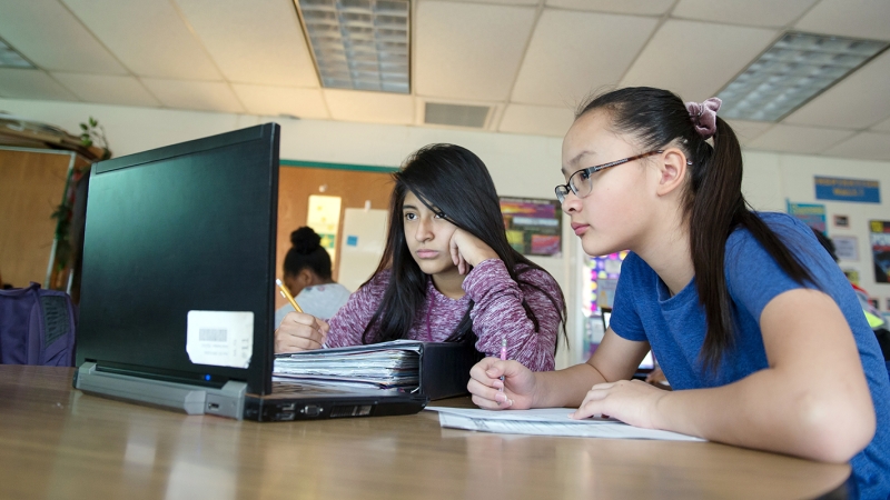 Photo of female students looking at a laptop