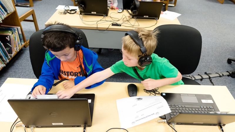 Two students in front of laptops working together on school work