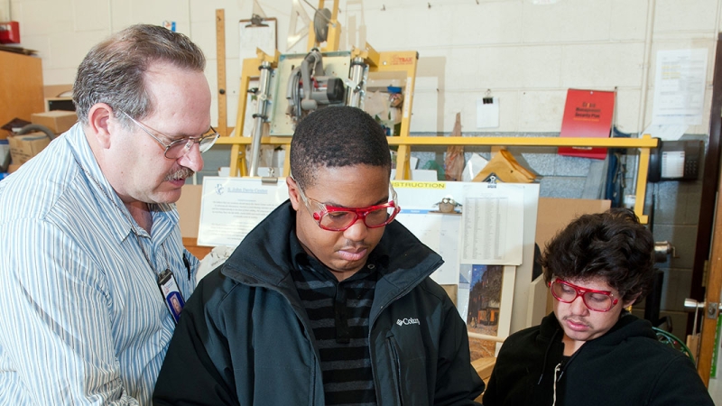 students working with teacher in technical education class